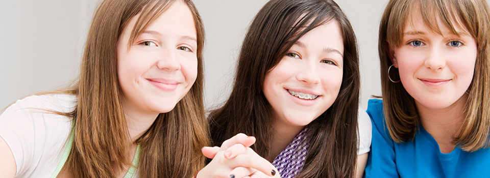 three teen girls sitting together, smiling